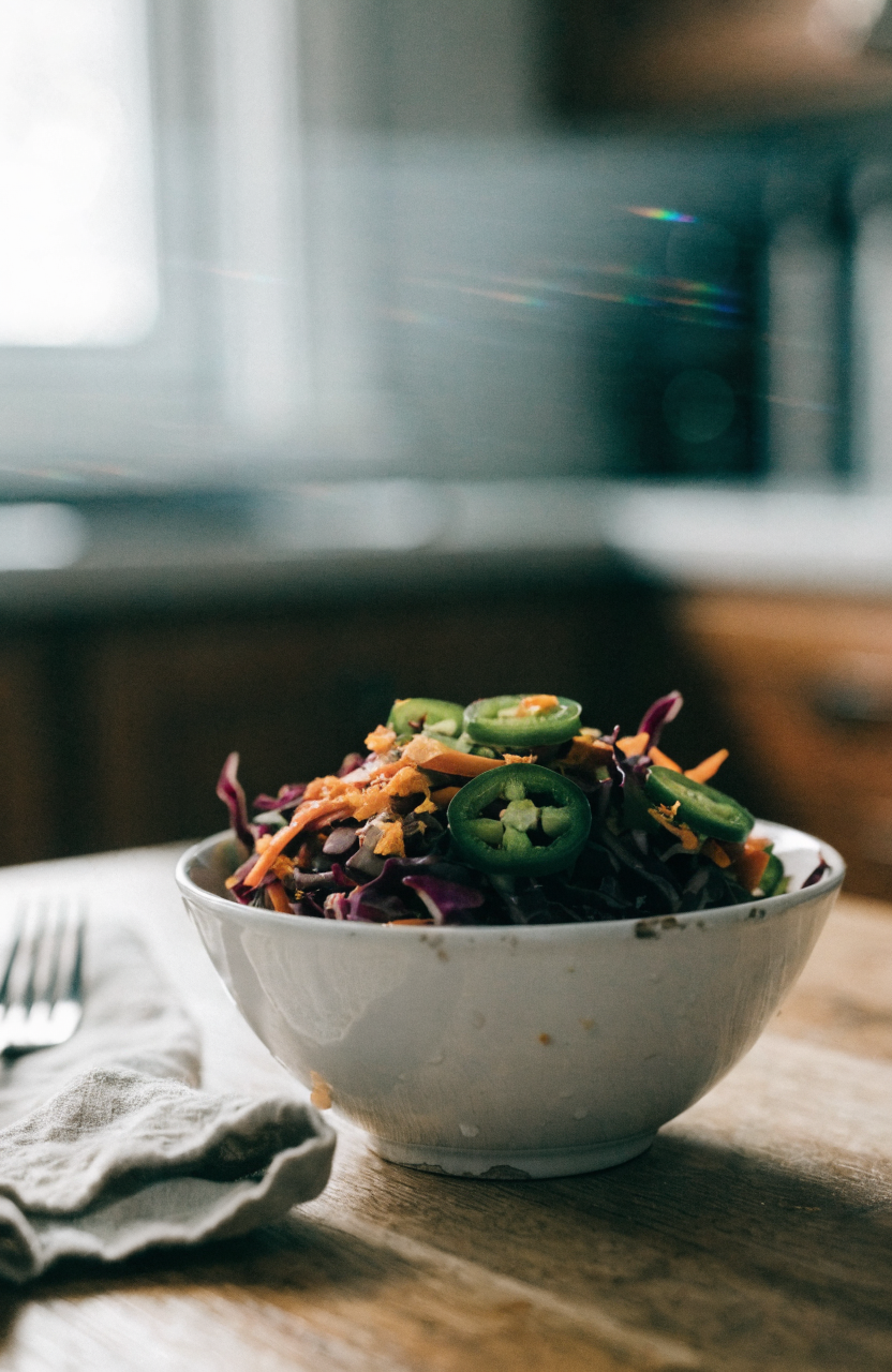 Spicy citrus coleslaw served in a white bowl with orange zest and jalapeño